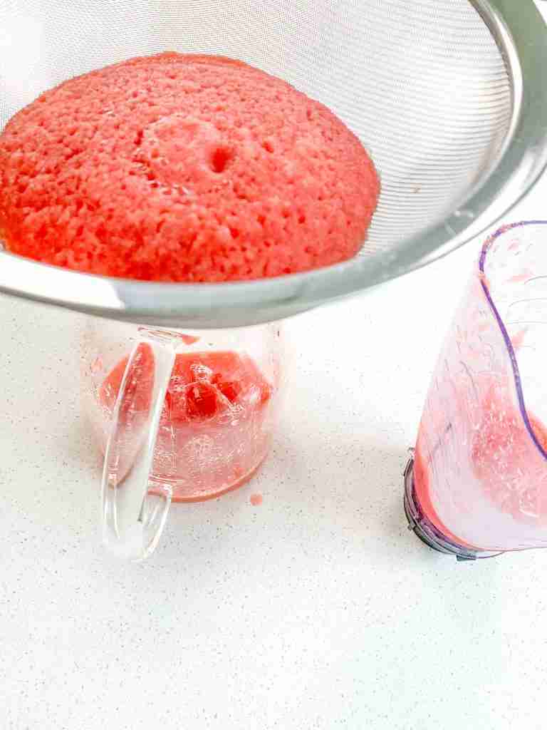 straining watermelon juice into a pitcher