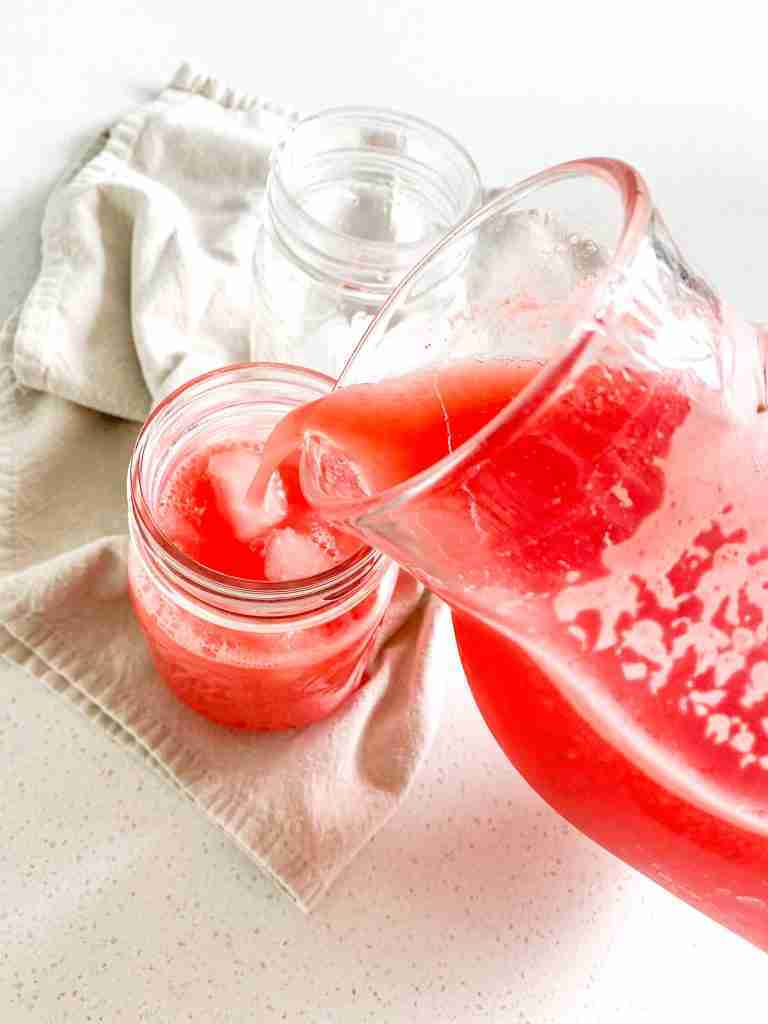pouring watermelon lemonade into a glass