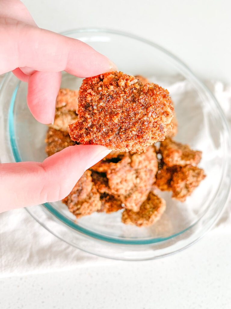 hand holding up a homemade Nashville hot chicken nugget