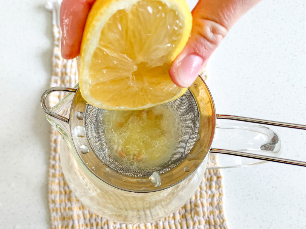 squeezing lemon into a pitcher over a strainer