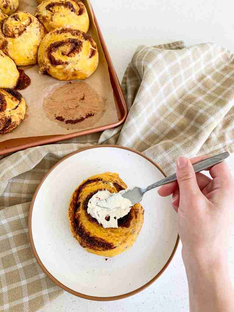 hand frosting a cinnamon roll