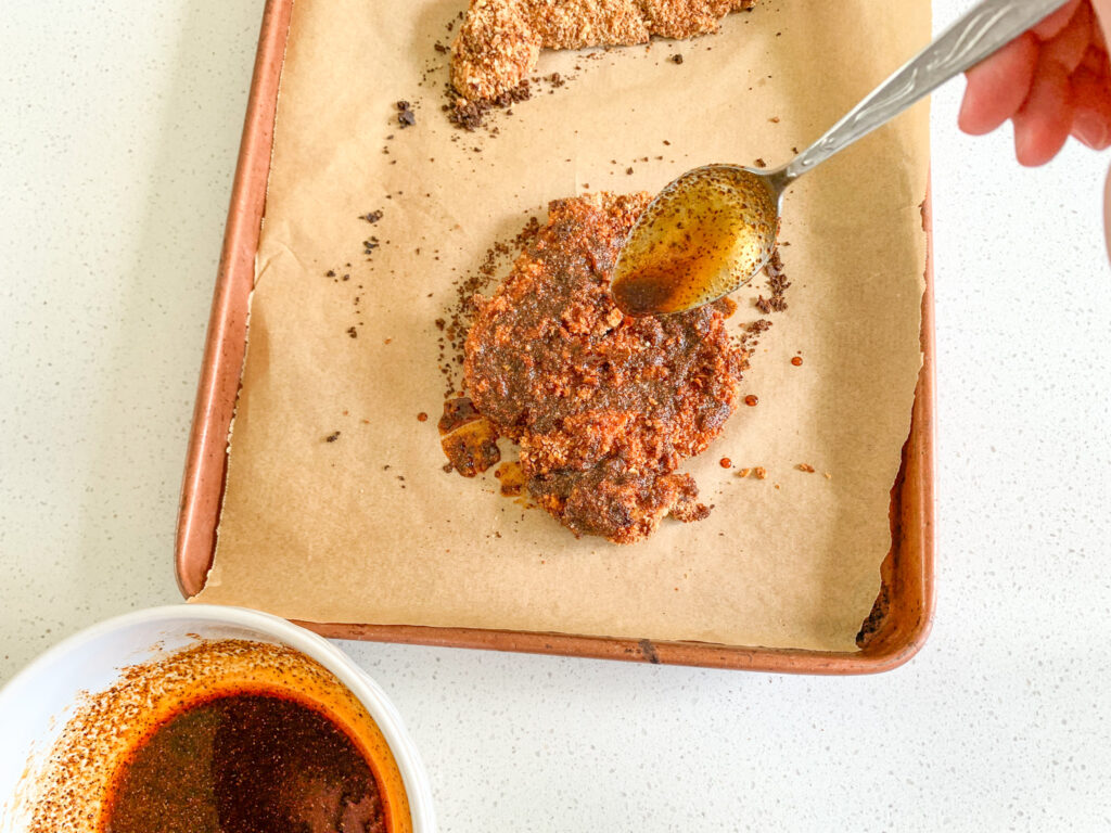 adding Nashville Hot Chicken spice to a breaded piece of chicken