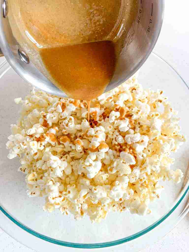 pouring peanut butter mixture over popcorn