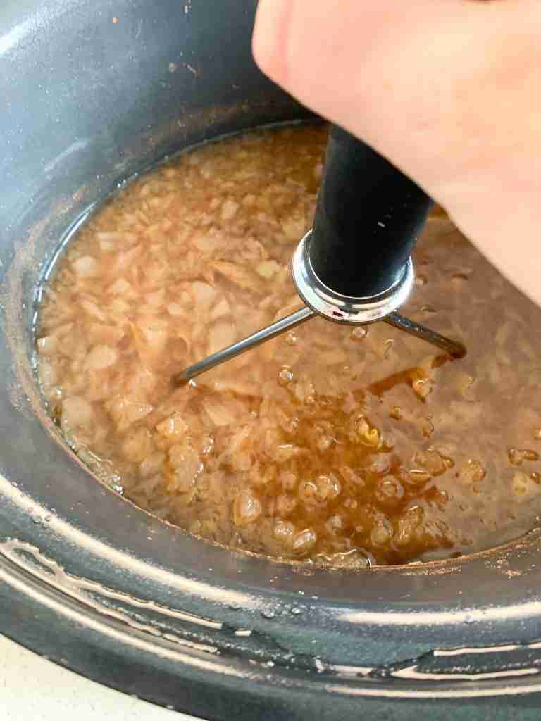 mashing apples in cider in slow cooker