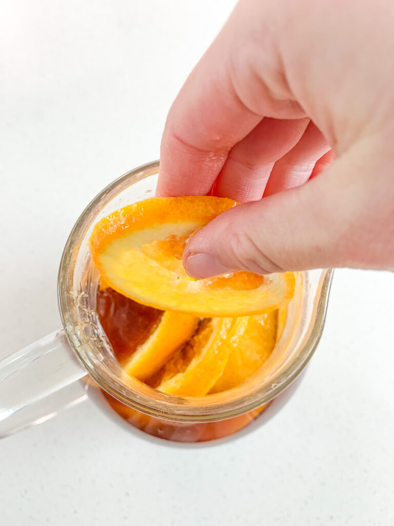 adding fresh orange slices into punch pitcher