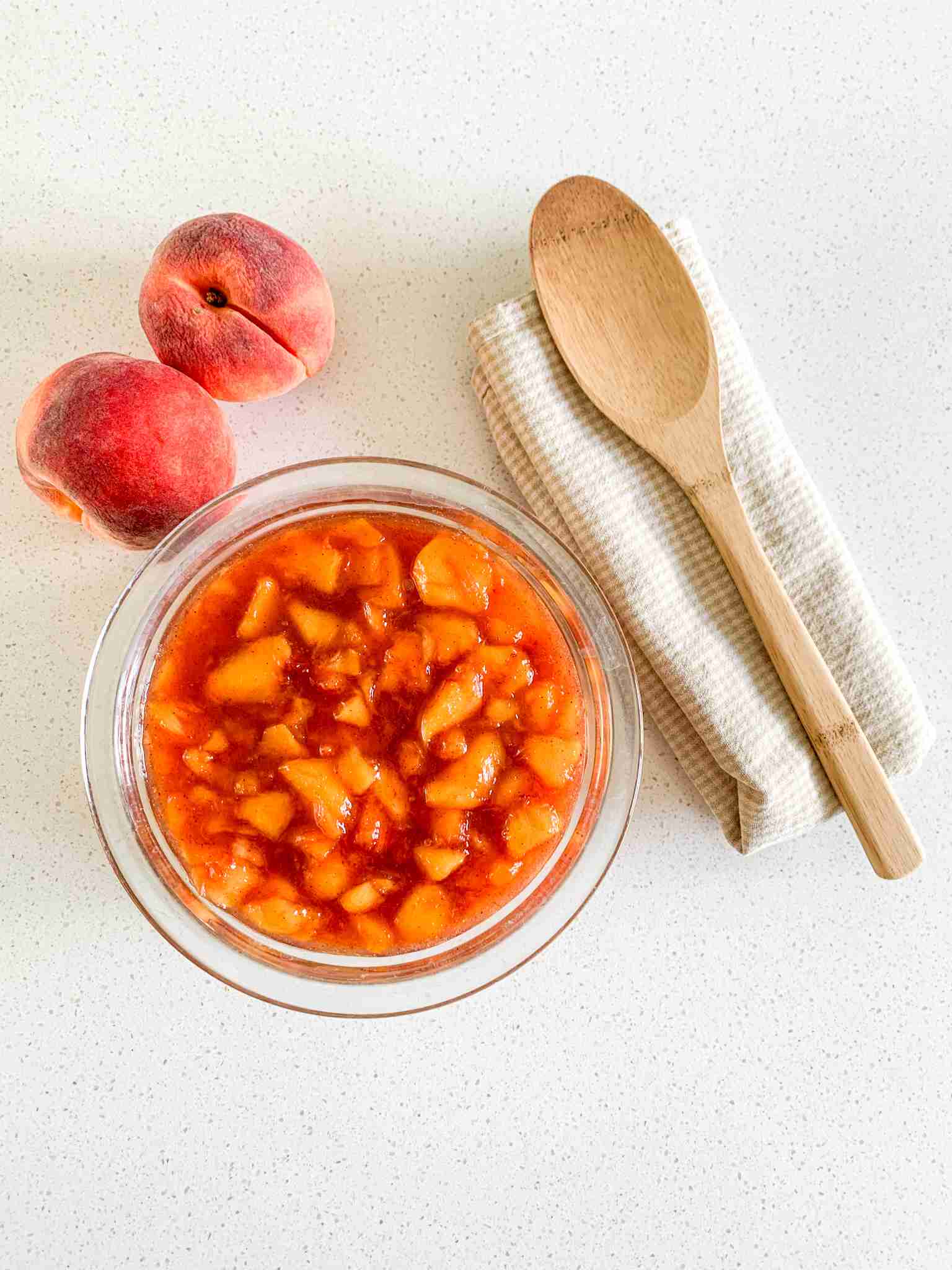 peaches with a wooden spoon for stirring and a bowl of peach filling