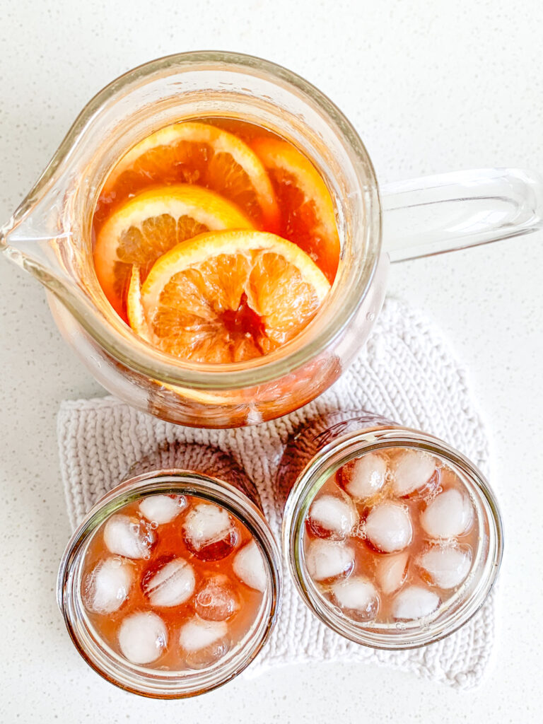 freshly made non alcoholic holiday punch in a pitcher and 2 glasses with ice