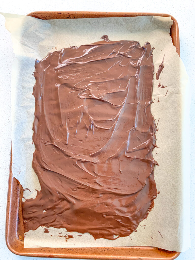 spreading melted chocolate on sheet pan for chocolate bark