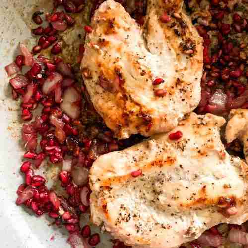 chicken breasts in skillet with pomegranates