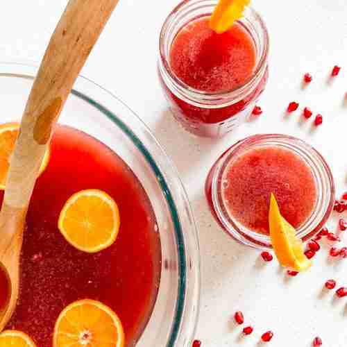 large punch bowl full of ingredients and 2 glasses ready to drink from