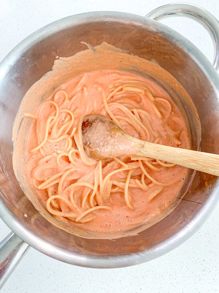 mixing cooked pasta and homemade sauce in a pot