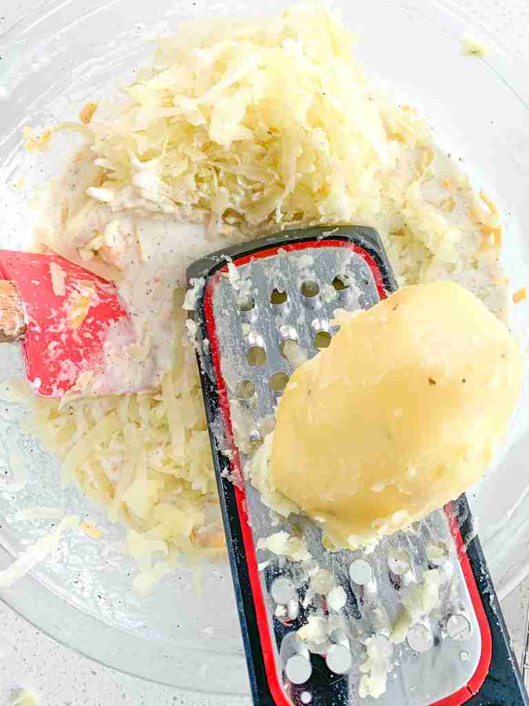grating cooked potatoes into mixture for hashbrown casserole