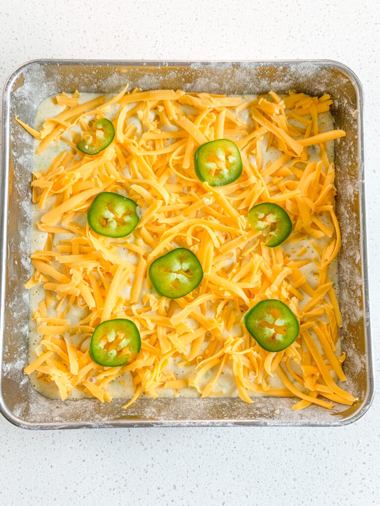 slices of jalapeno on top of corn casserole ready to be baked