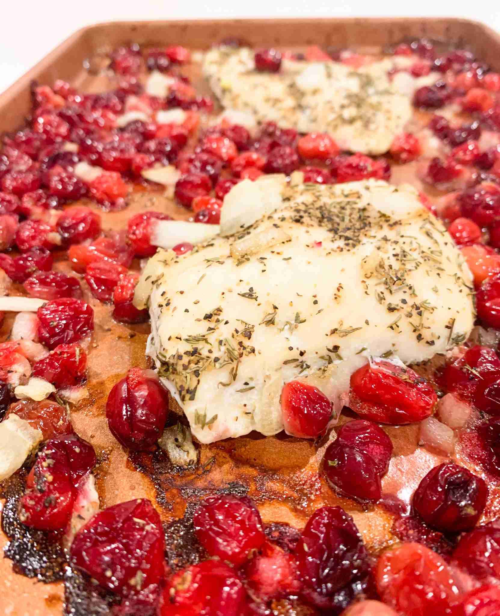 up close shot of chicken and cranberries on a pan