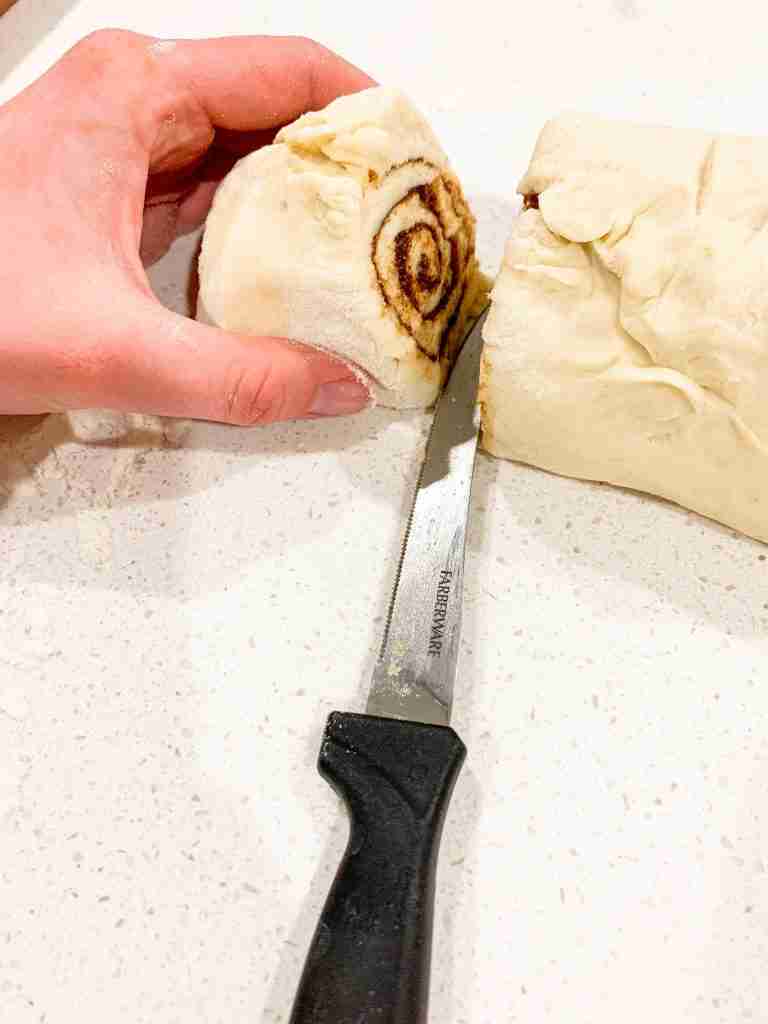 hand cutting cinnamon buns