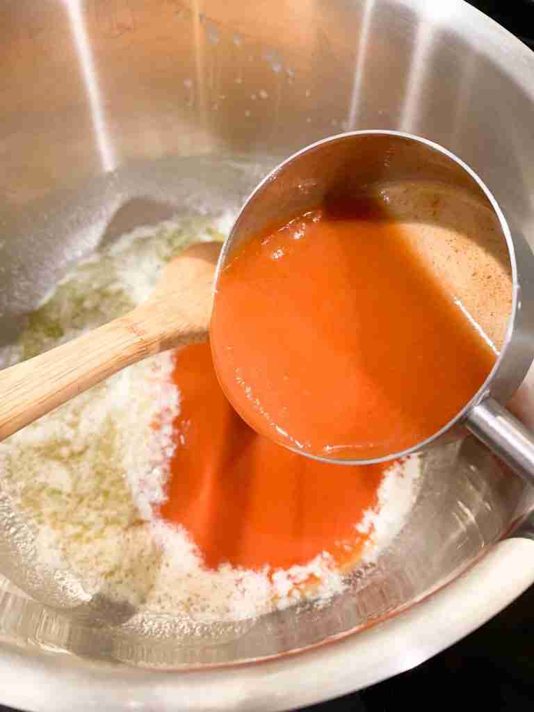 measuring cup adding in hot sauce to the pan of melted butter