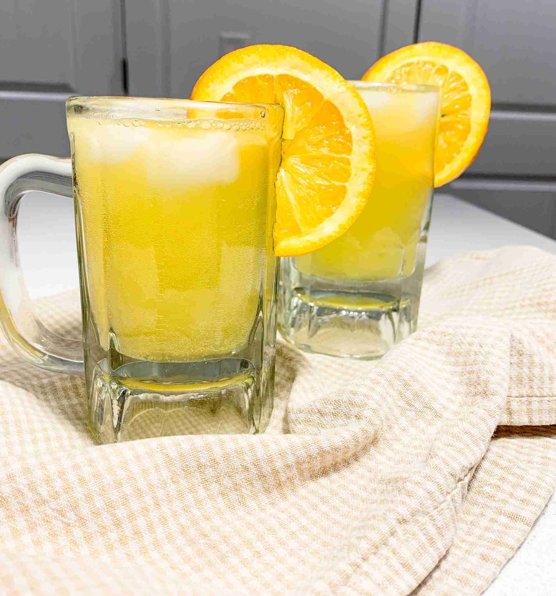 2 mugs of fizzle orange drinks with a orange slice