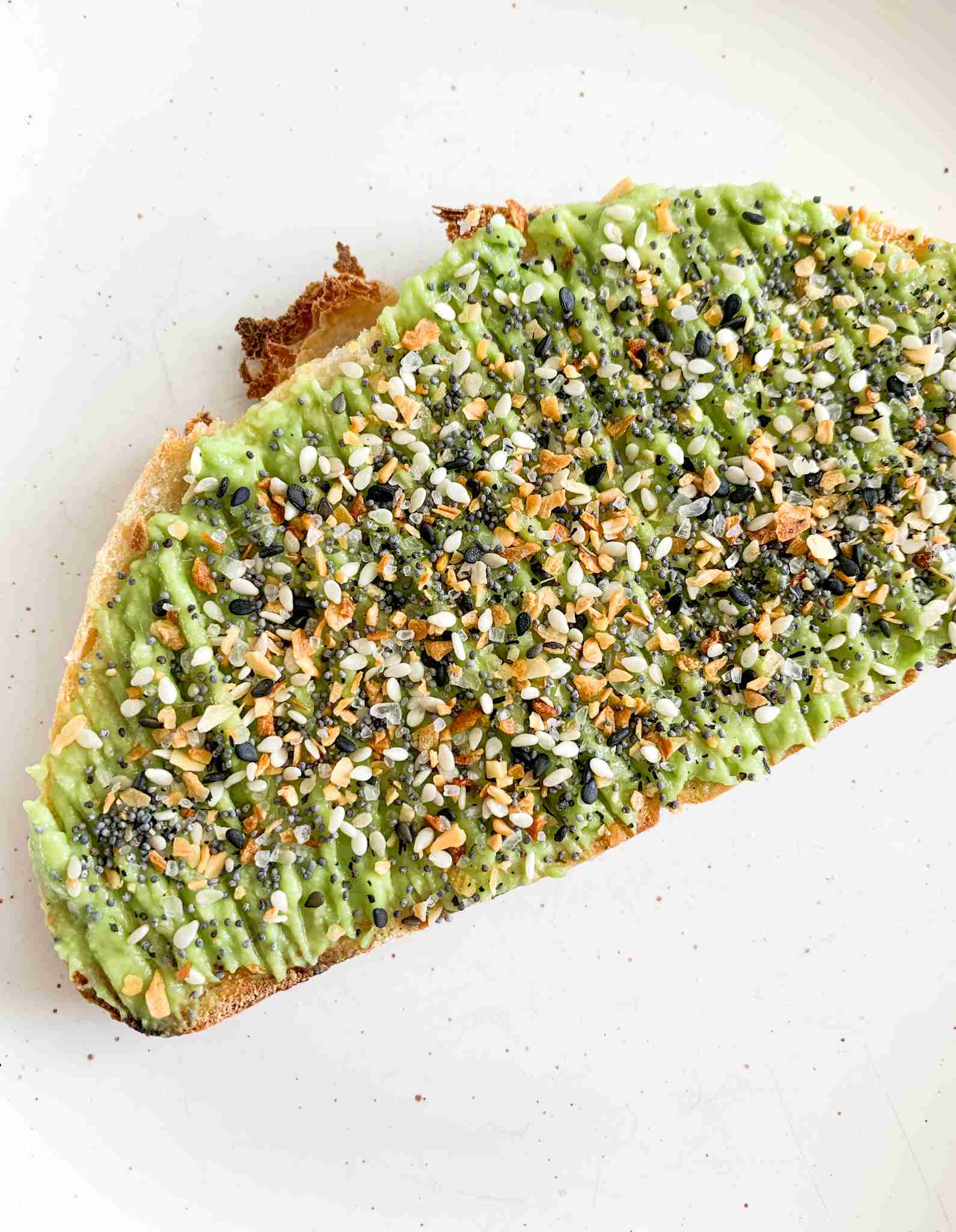 large slice of toast with mashed avocados and seasoning