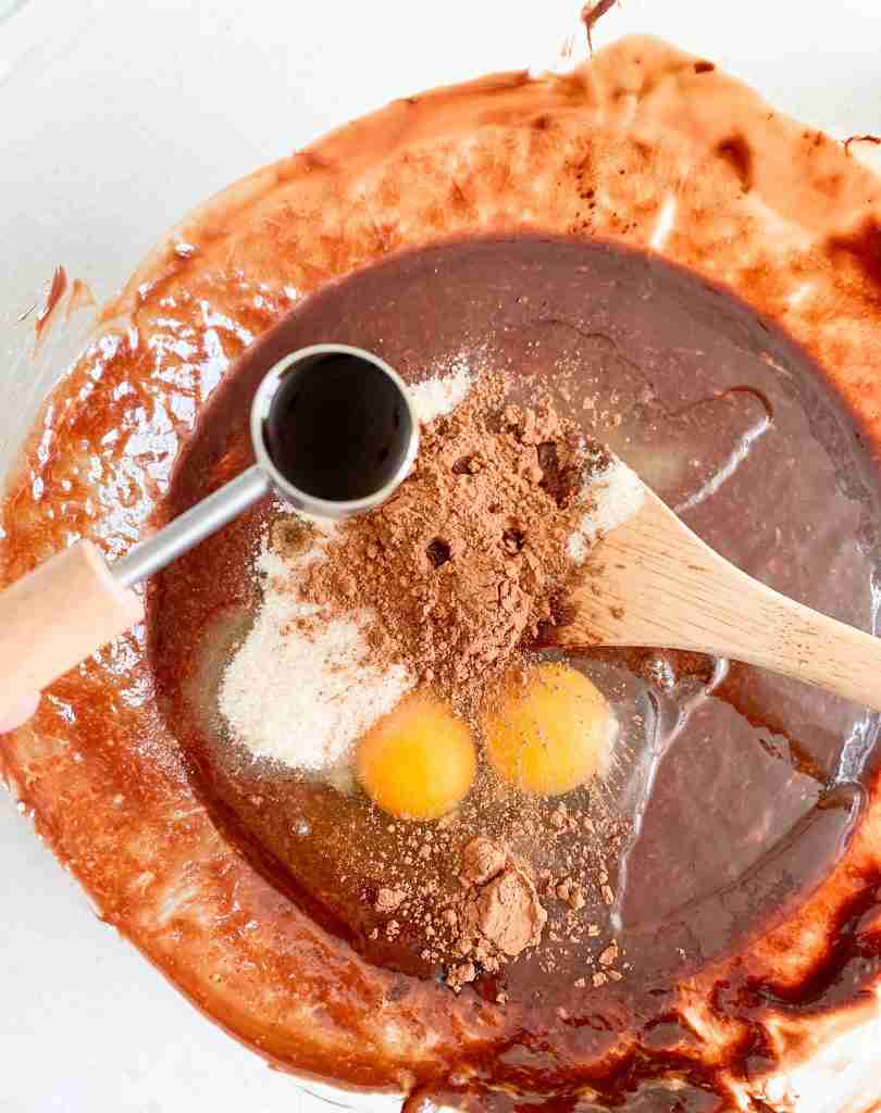 adding in vanilla extract and other ingredients to a bowl 