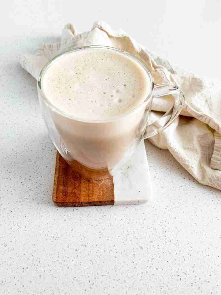 mug of coffee with foam on top of it with a towel behind it