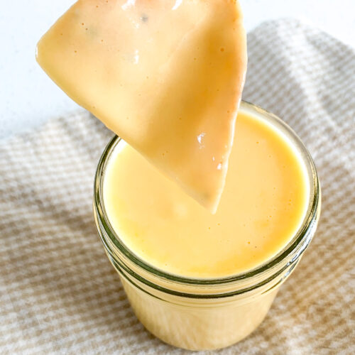 dipping a chip in cheddar cheese dip