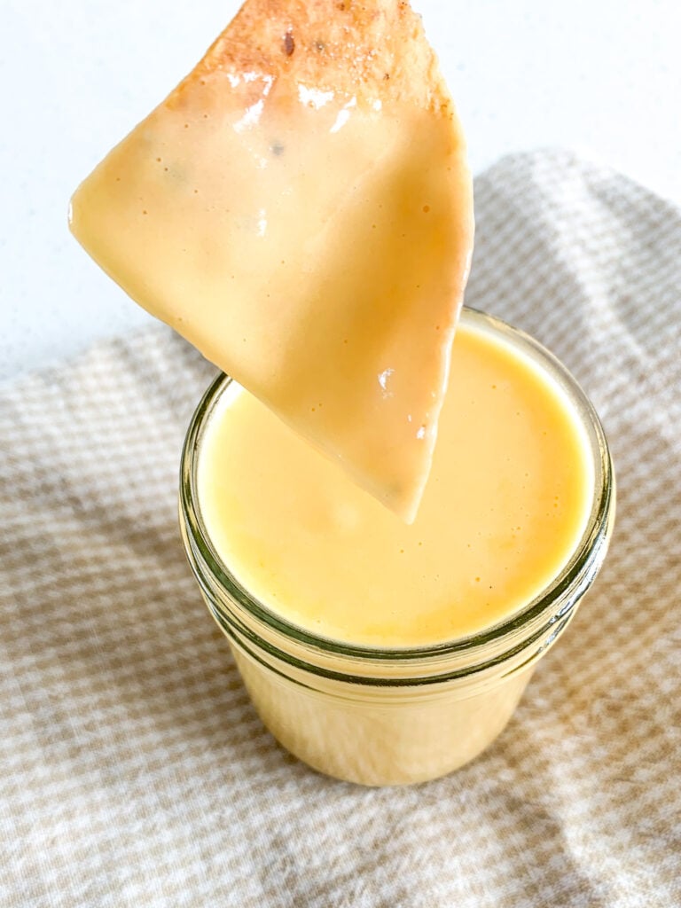 dipping a chip in cheddar cheese dip