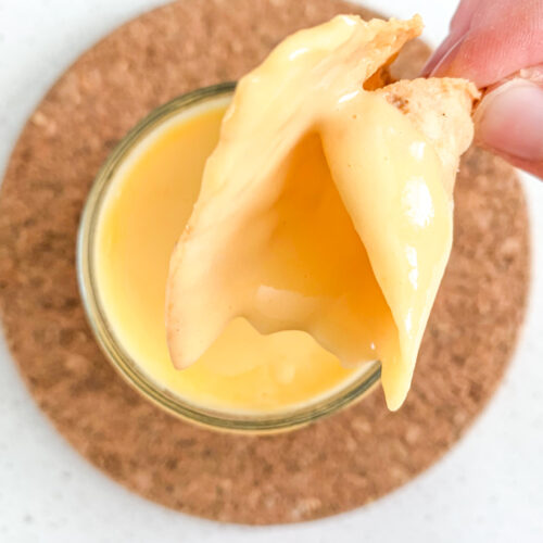 dipping a chip in cheddar cheese dip