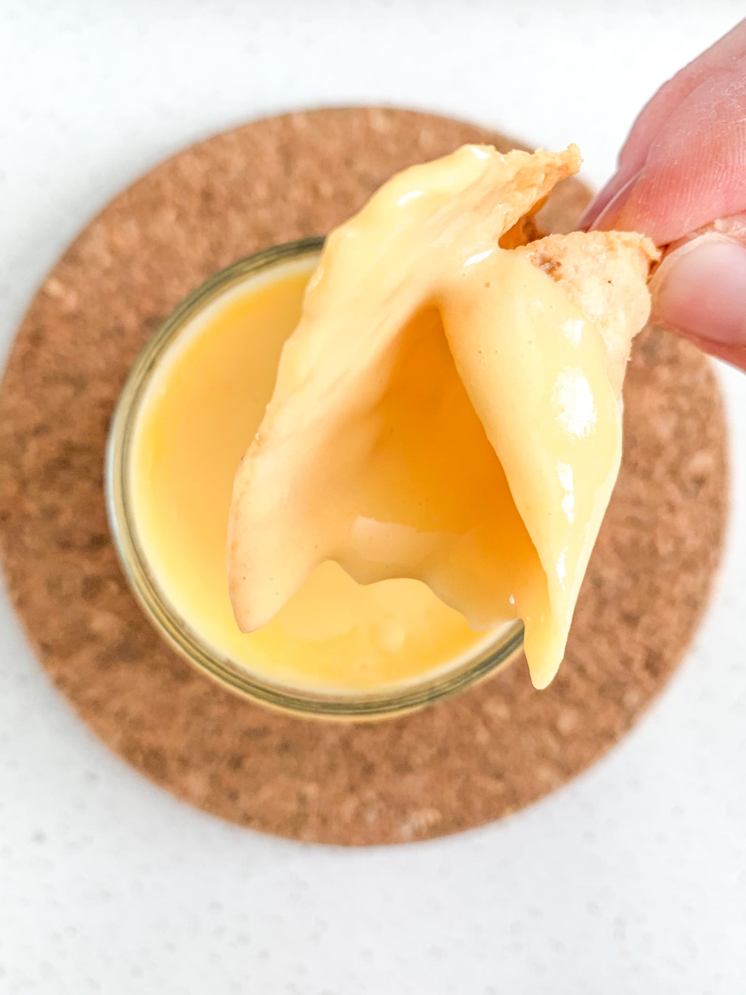dipping a chip in cheddar cheese dip