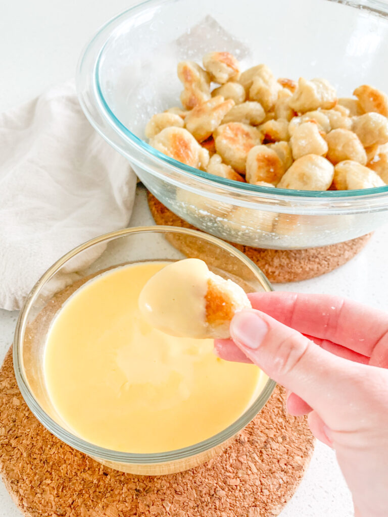 freshly baked sourdough pretzel bites getting dipped in cheese