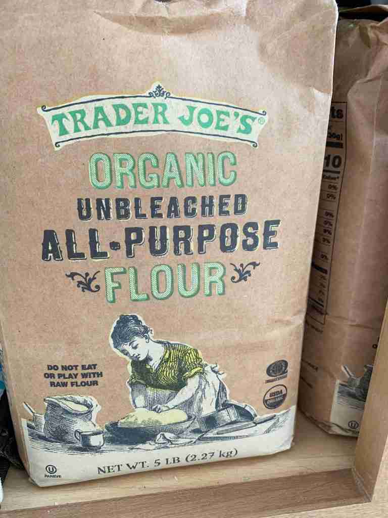 bags of trader joes unbleached all purpose organic flour in a cabinet