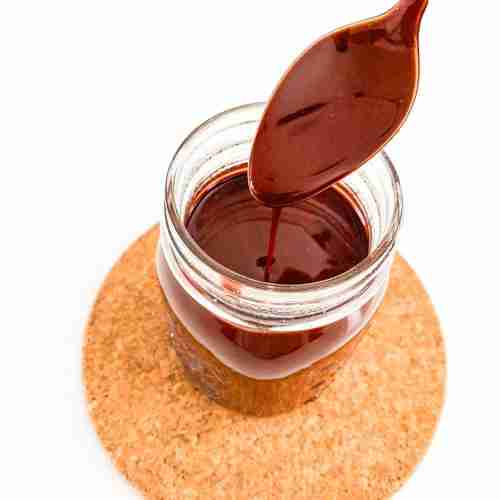 jar of chocolate with a spoon drizzling the chocolate above