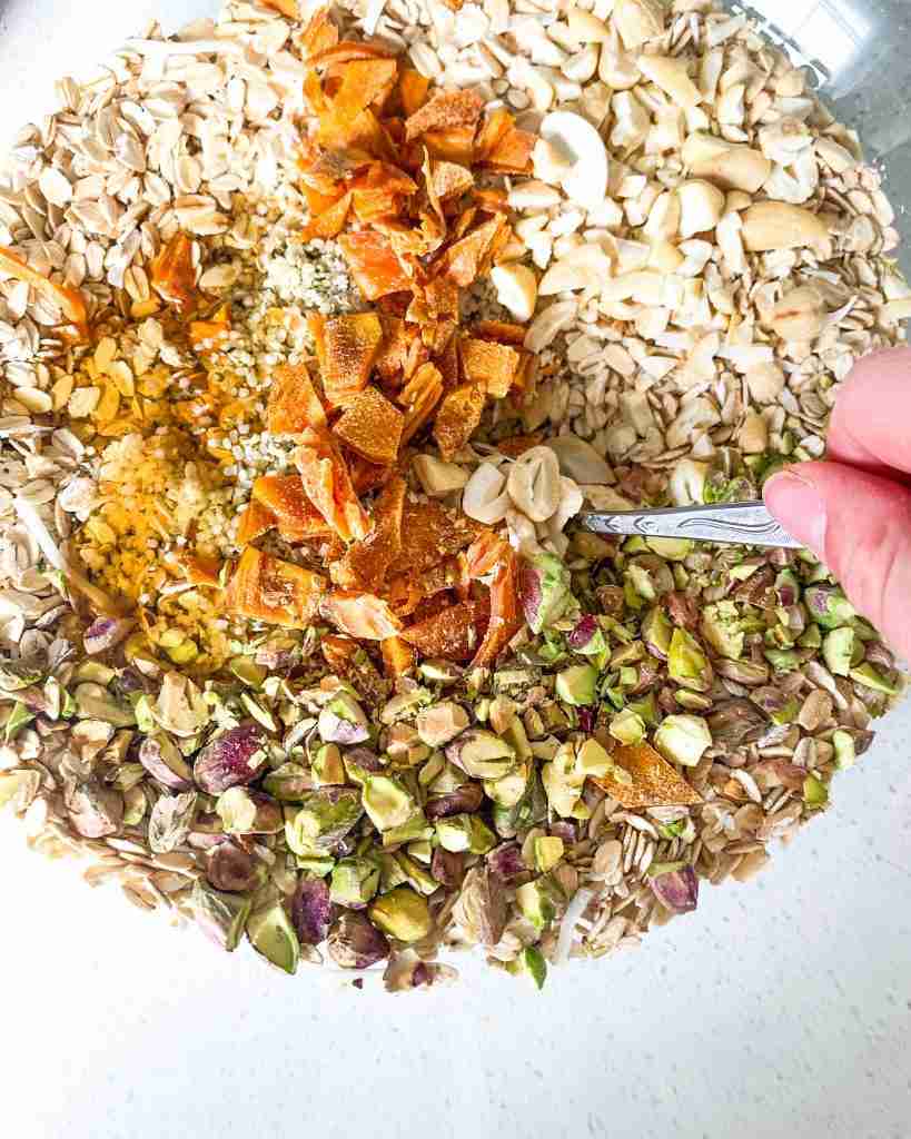 mixing oats, nuts, seeds, fruit in a bowl