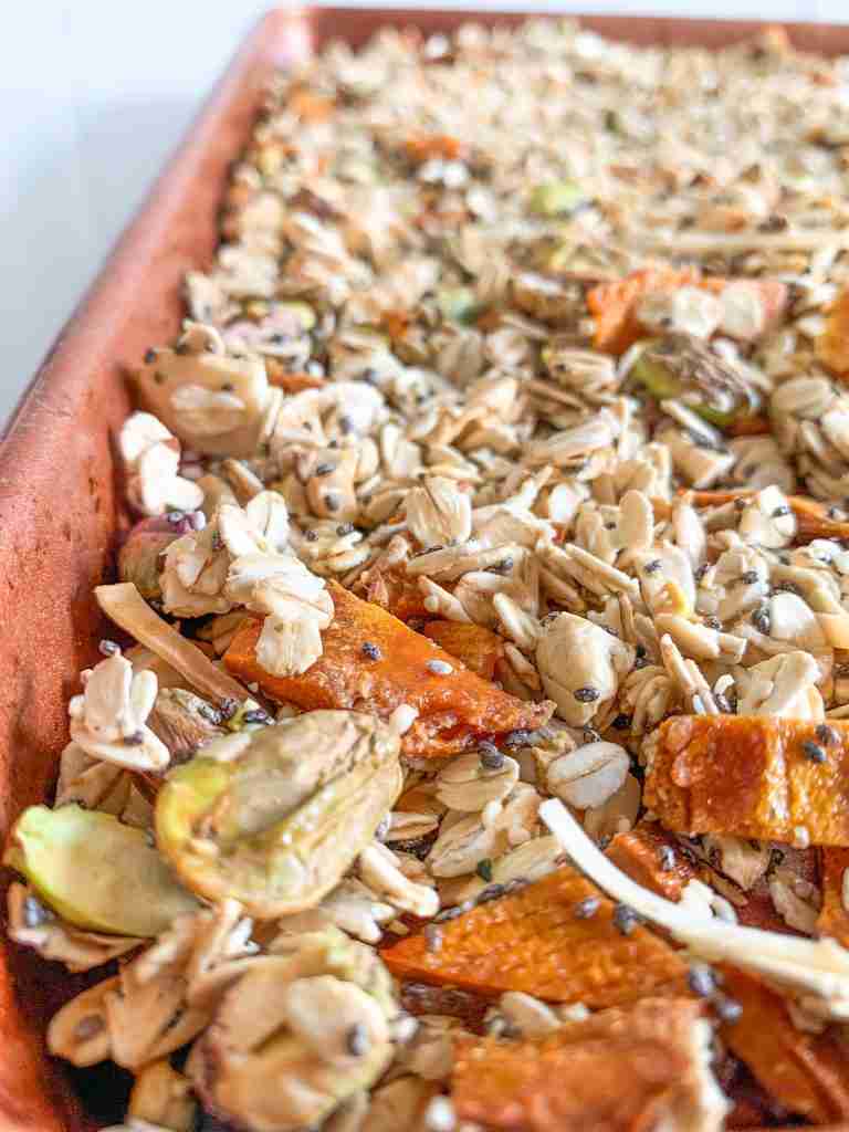 upclose photo of dried fruit, nuts, oats, and seeds on a sheet pan