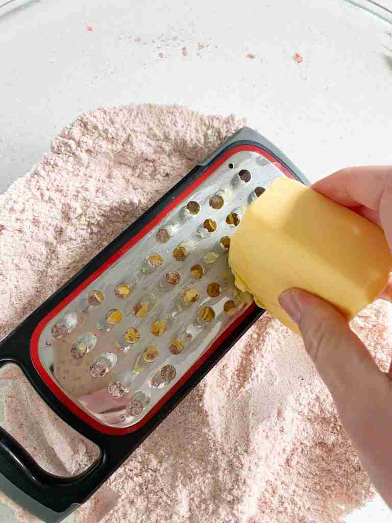 hand grating butter into a bowl 