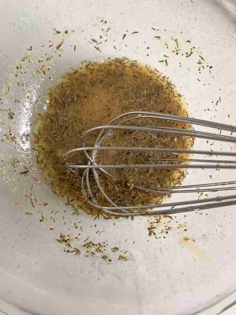 whisking herbs and juice together in a bowl