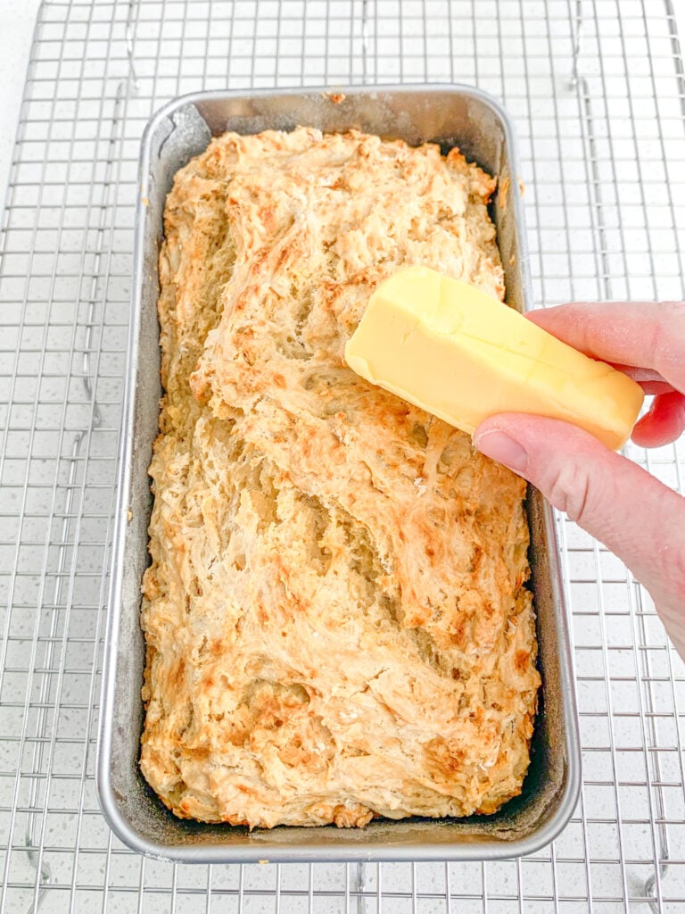 sourdough beer bread just out of the oven getting topped with butter