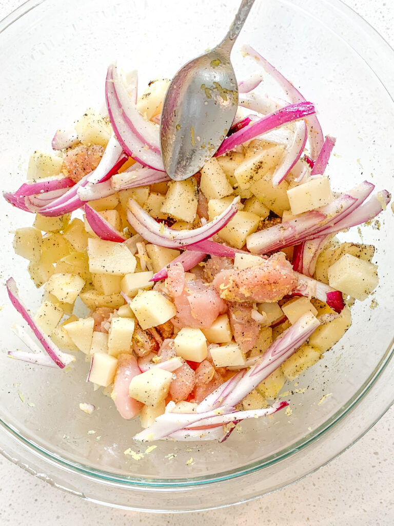 all ingredients in a bowl getting mixed for sheet pan meal