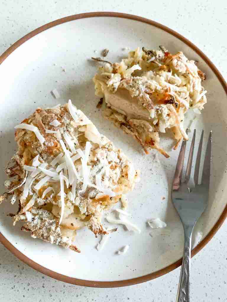 piece of breaded chicken on a plate cut in half with a fork