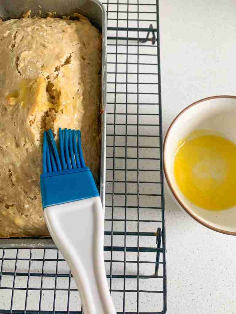 brush brushing on melted butter on a loaf of bread 