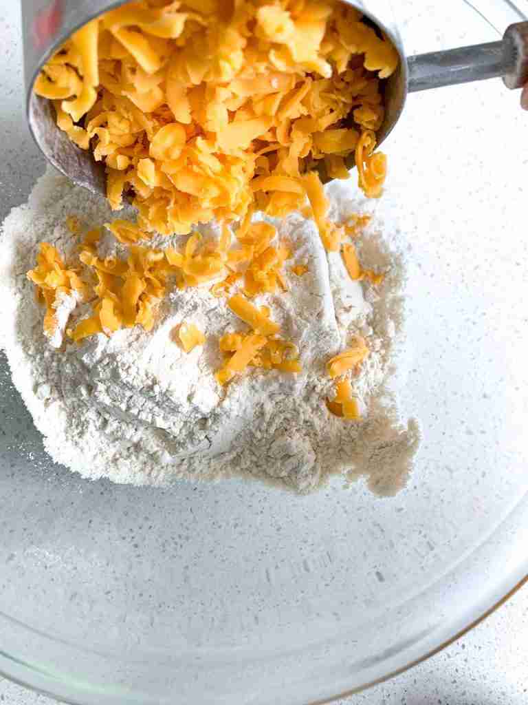 grated cheese being added into a bowl 