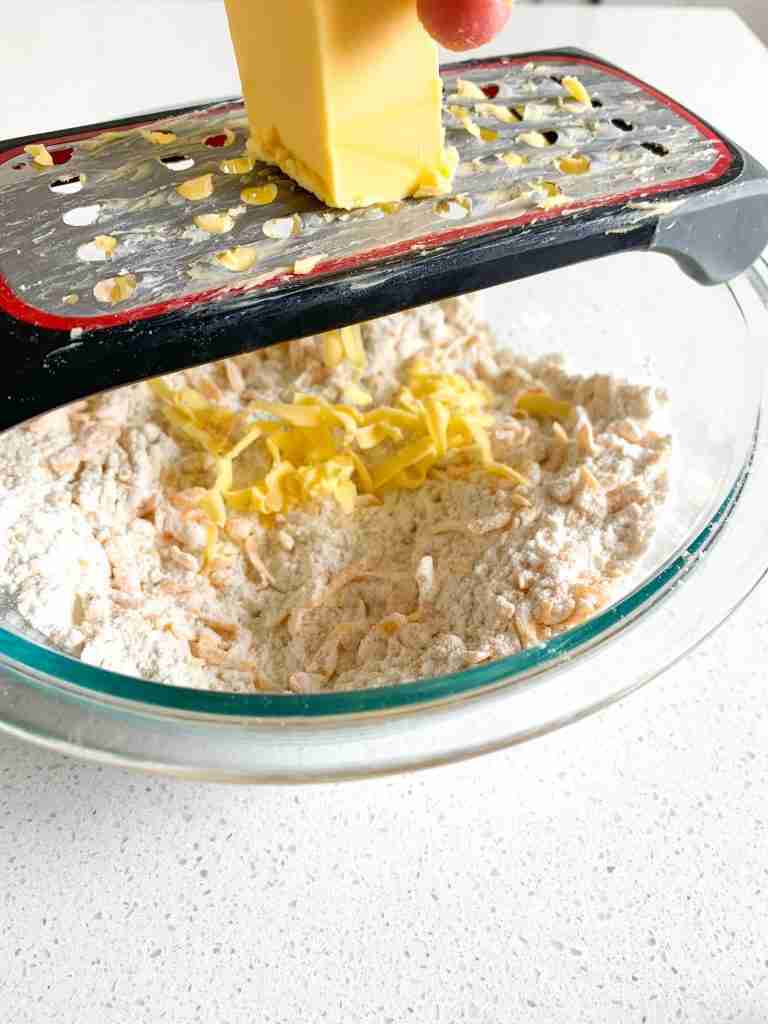 butter being grated into a bowl 