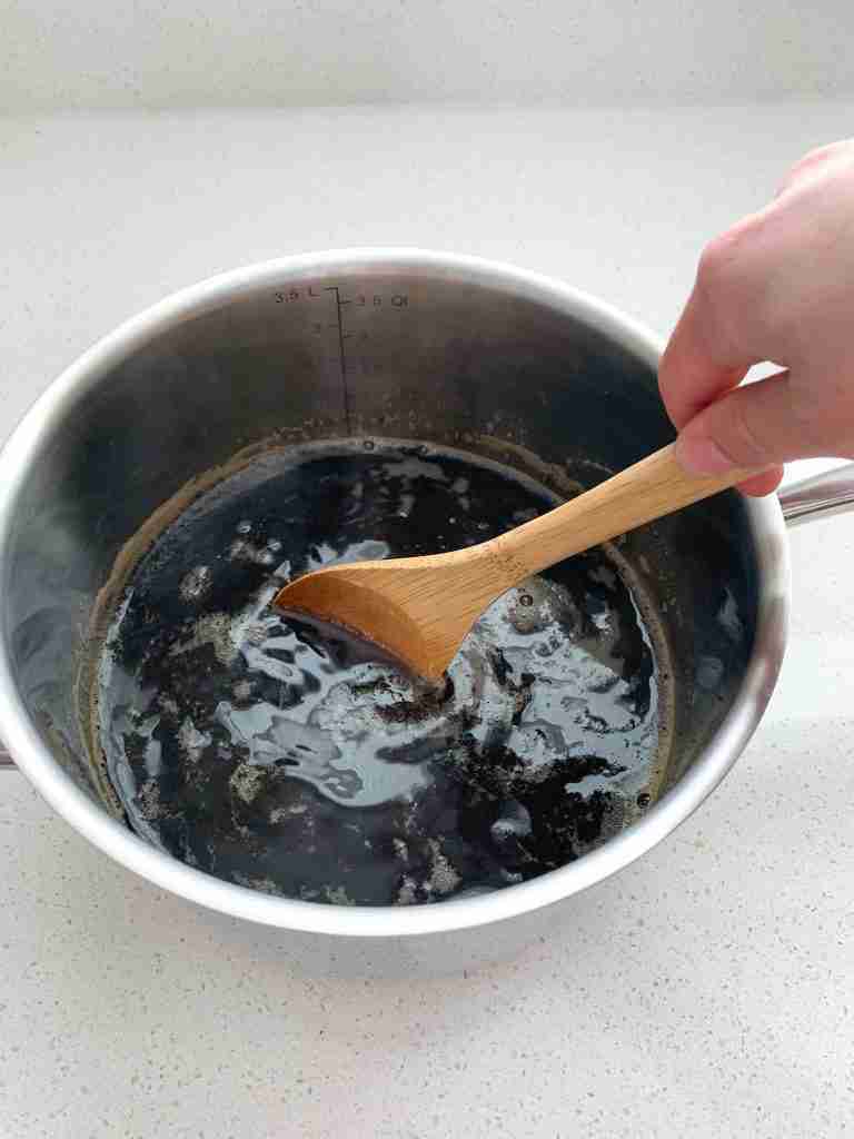 hand stirring a pot of tea on the countertop