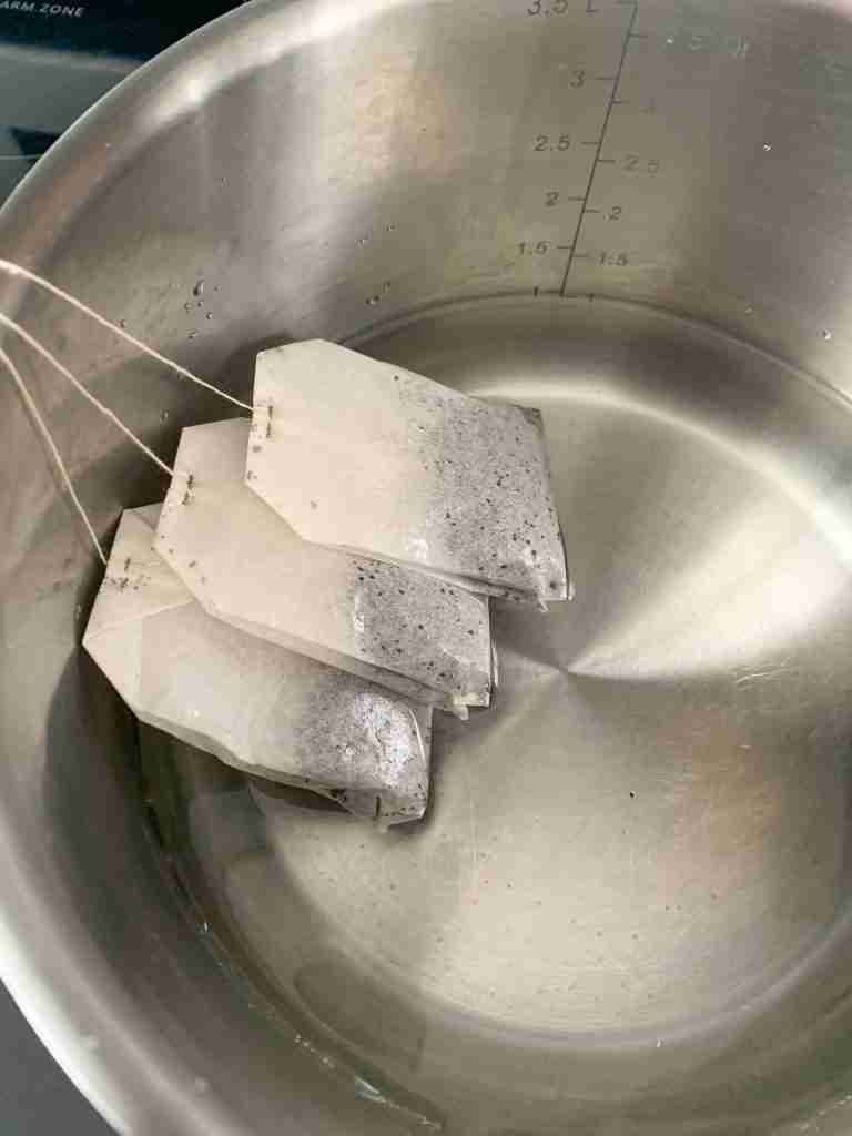 3 tea bags seeping in a pot of water