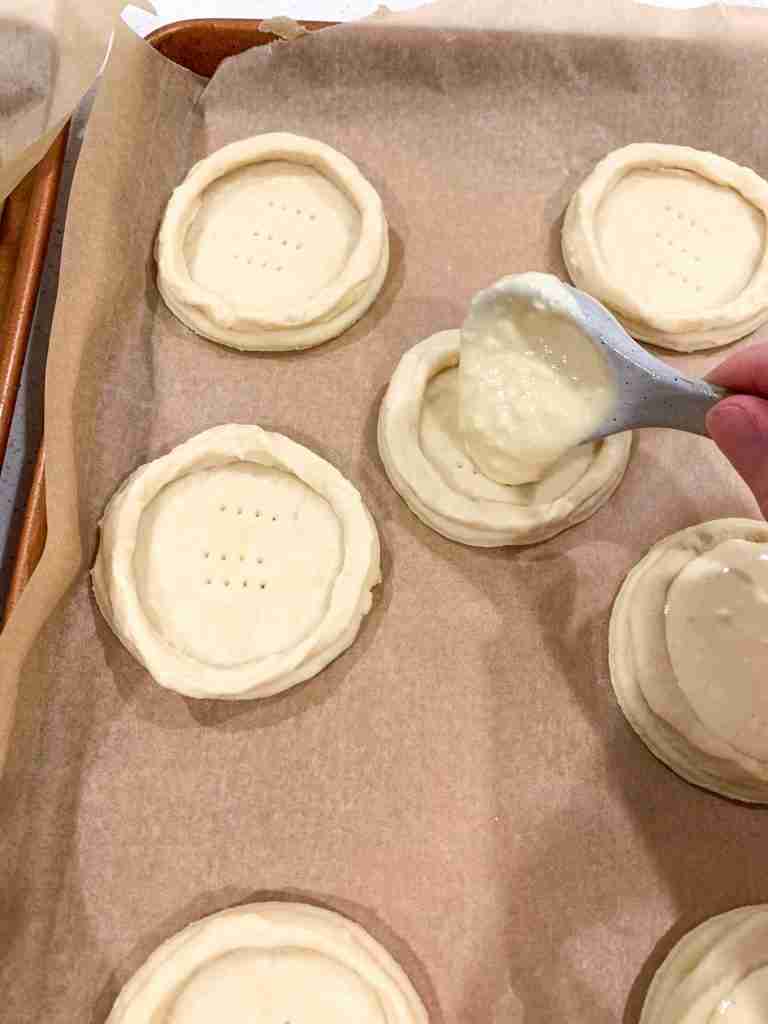 hand putting cheese filling into dough circles