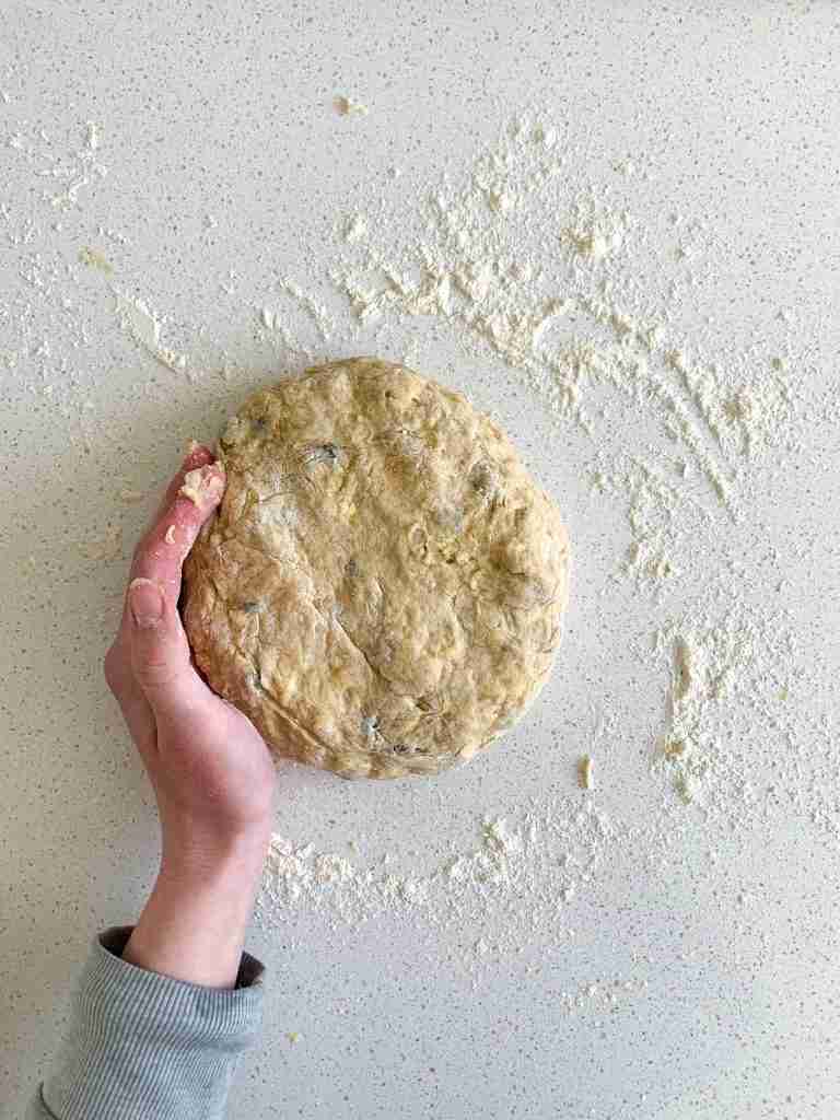 hand shaping dough on a counter top