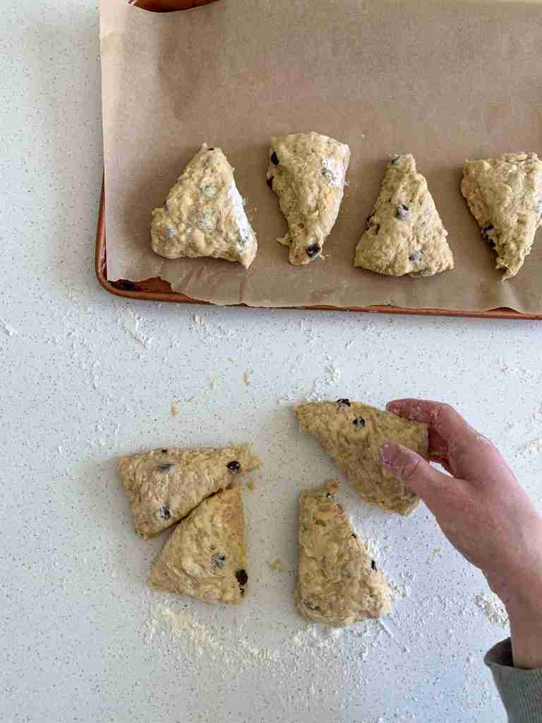 hand putting scones on a baking sheet