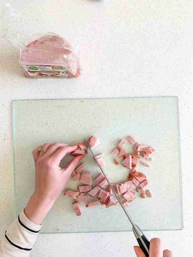 person slicing ham into chunks