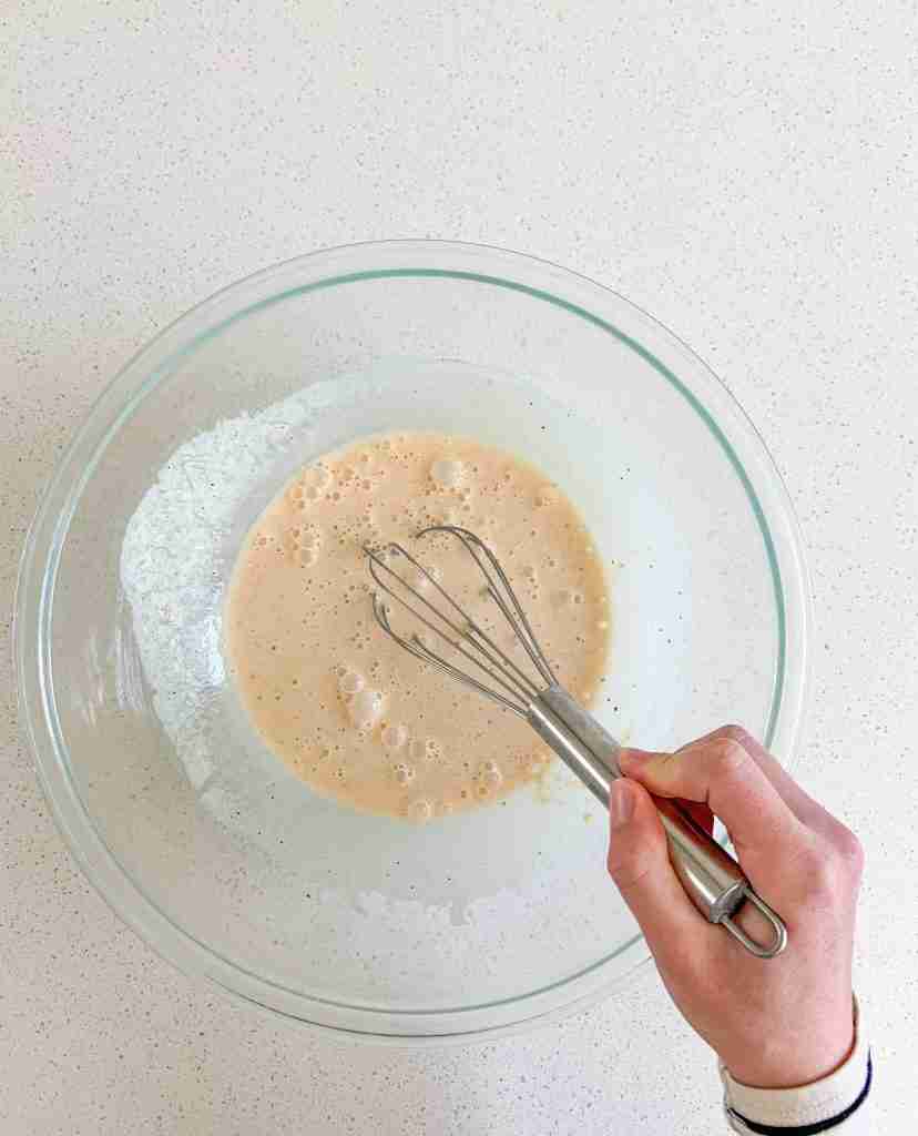 hand whisking ingredients of the custard in a bowl 