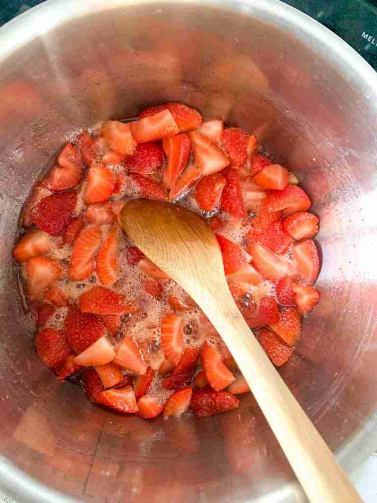 spoon stirring strawberry mixture in a pan