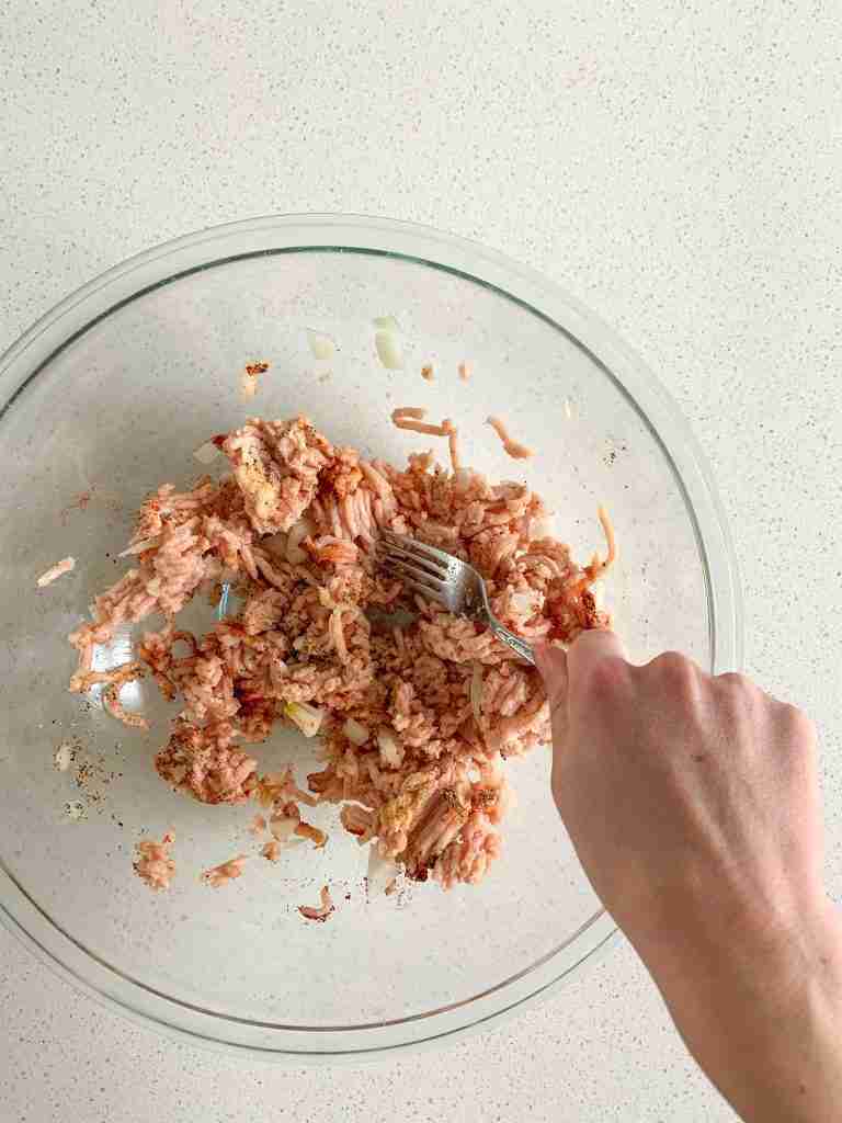 hand combining ground chicken and spices